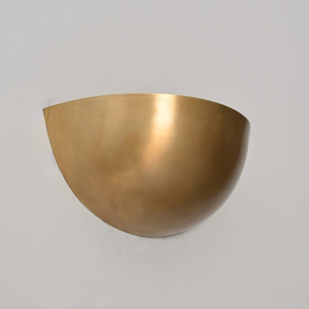 Modern half-sphere brass wall-mounted light fixture on a gray background
