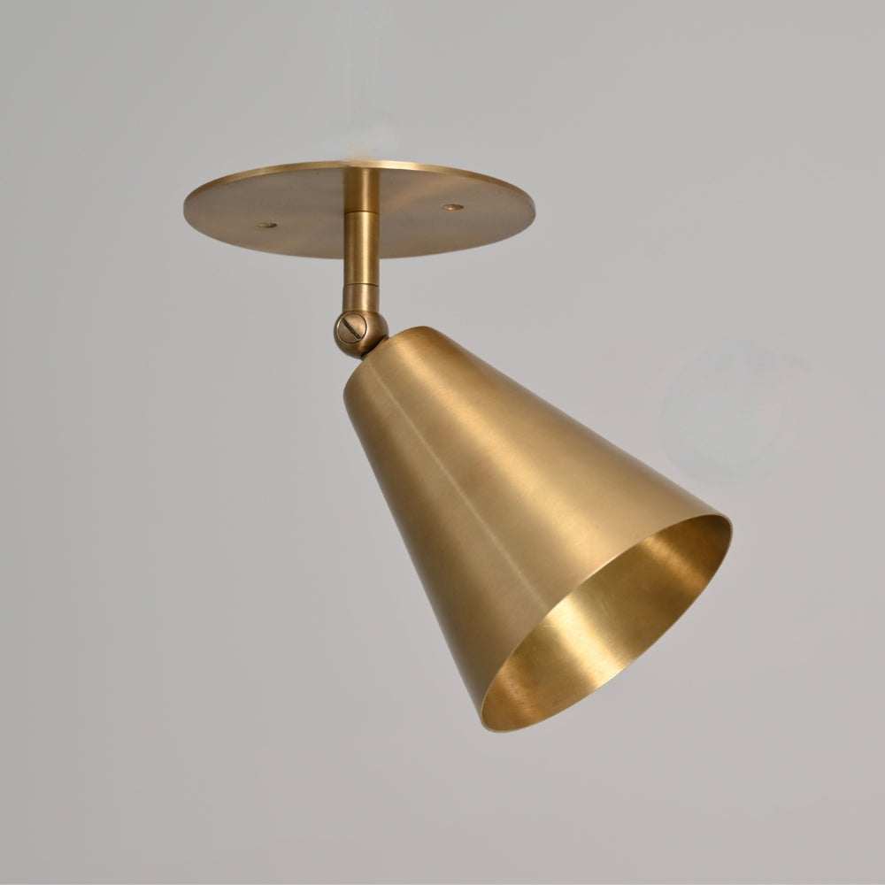 Modern brass cone wall sconce on a gray background 